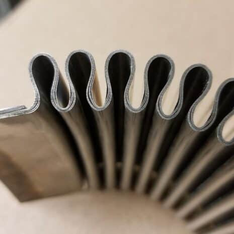 1407 series 5 ply exhaust capsules & expansion joints Steel coil with scalloped edges, showcasing industrial metal fabrication expertise.