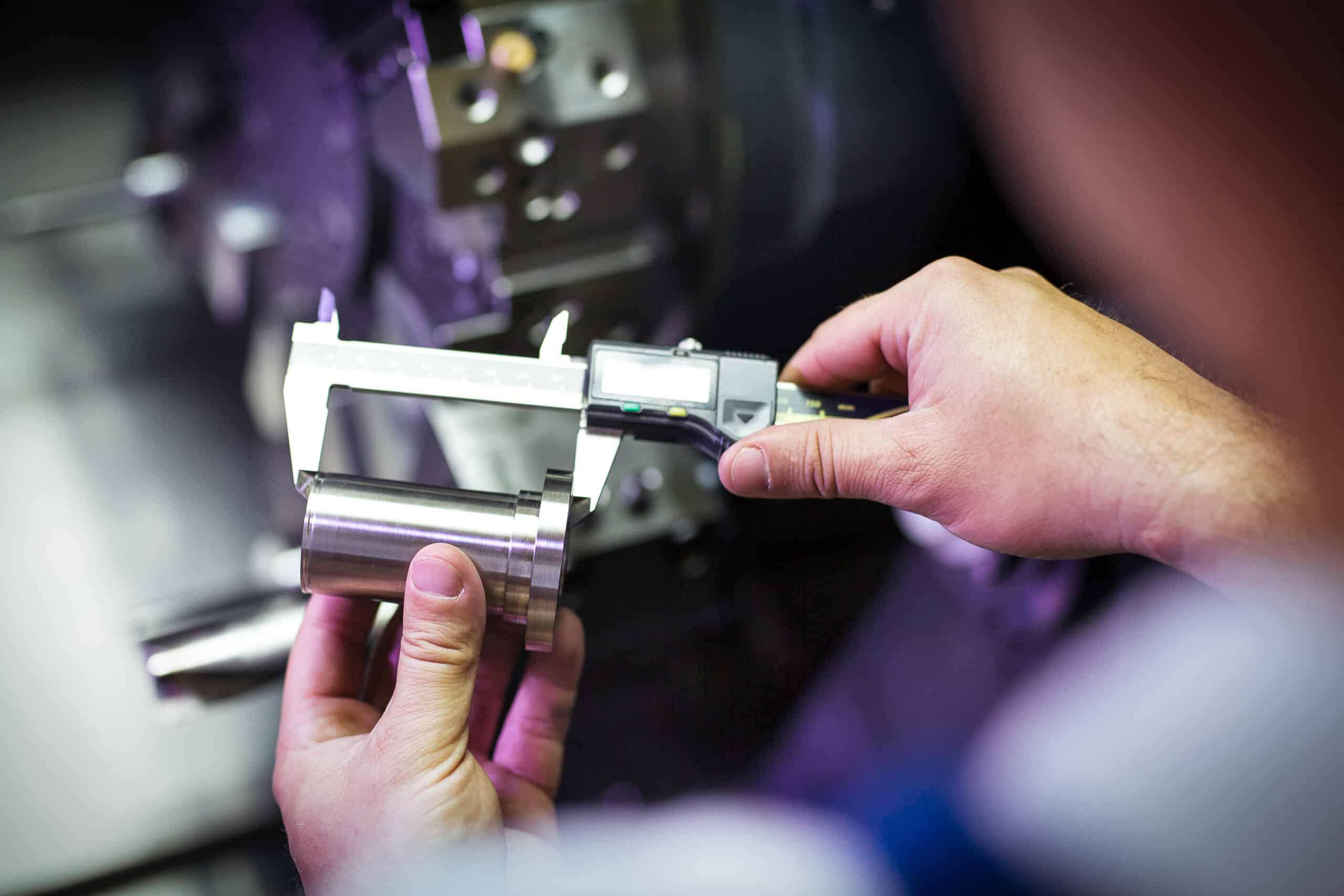Precision measurement of metal components using digital caliper for quality control in manufacturing.