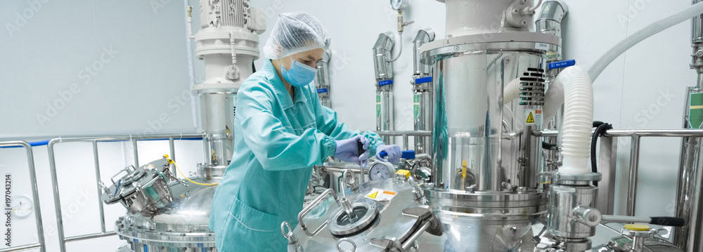 Stainless steel pharmaceutical manufacturing equipment in a cleanroom environment.