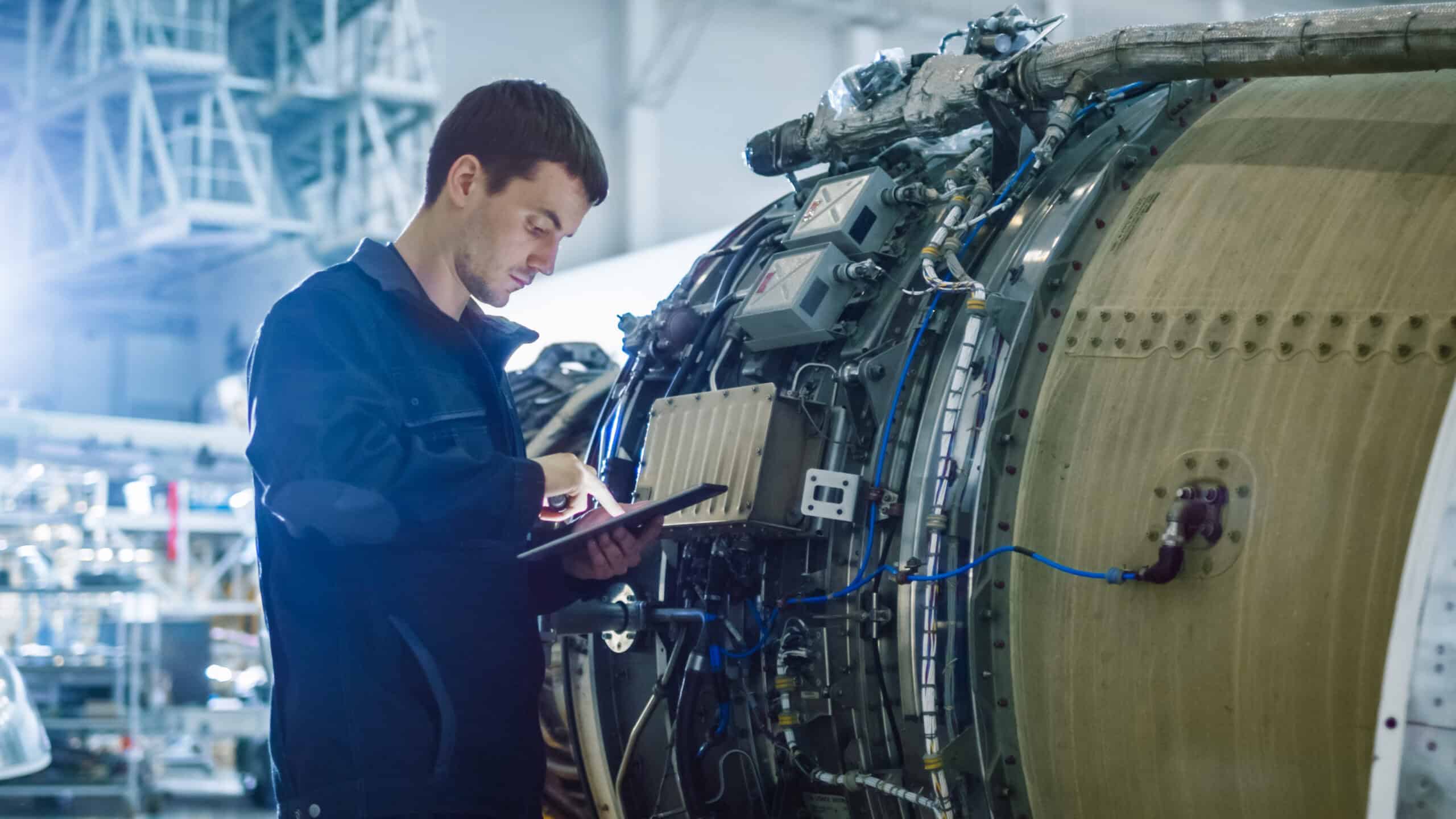 High-tech aircraft engine being inspected by a technician in an aerospace manufacturing facility.