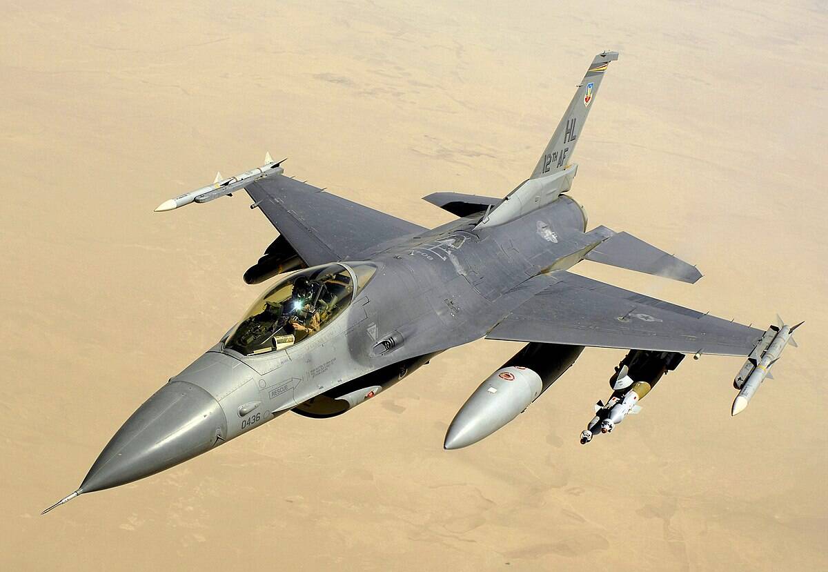 F-16 fighter jet in flight over desert landscape, showcasing advanced military aircraft technology.