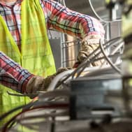 High-angle view of construction worker in safety gear handling industrial piping at a worksite.