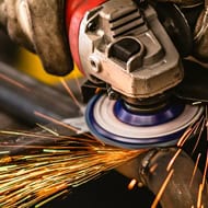 High-powered angle grinder polishing metal with sparks flying.