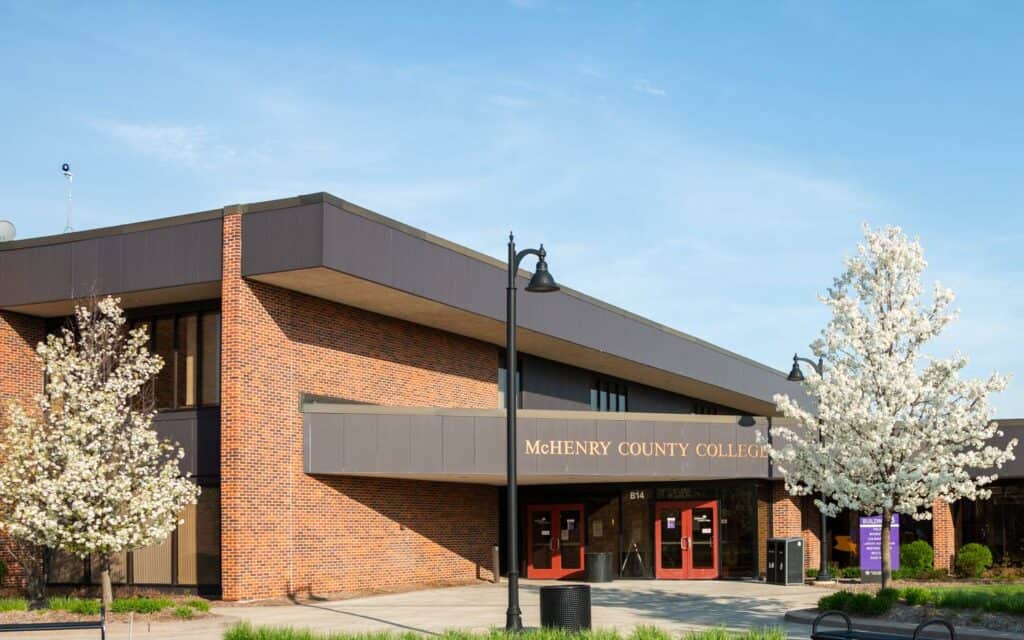 Modern college building with brick walls and blooming white trees at McHenry County College.
