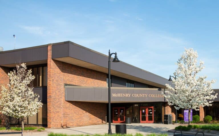 Modern college building with brick walls and blooming white trees at McHenry County College.