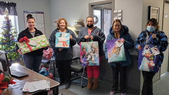 Festive office employees holding Christmas gifts in a holiday celebration.