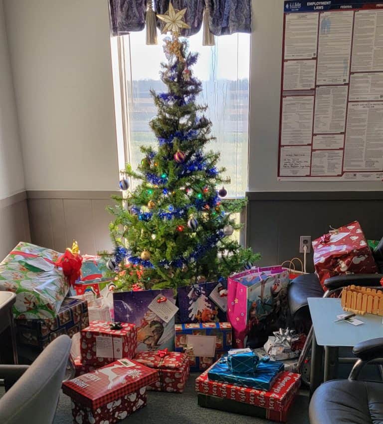 Christmas tree with colorful ornaments and gifts in an office setting, festive holiday décor and Christmas wrap.