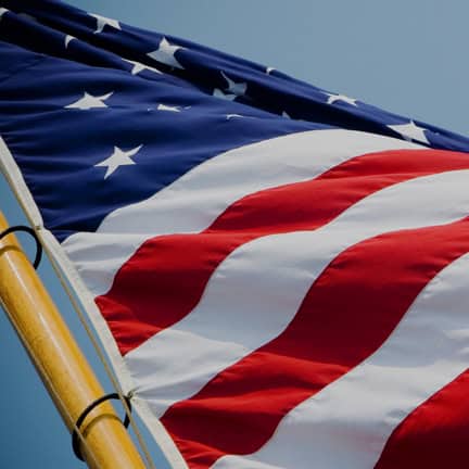 Vivid American flag waving on a clear blue sky, representing patriotism and national pride.